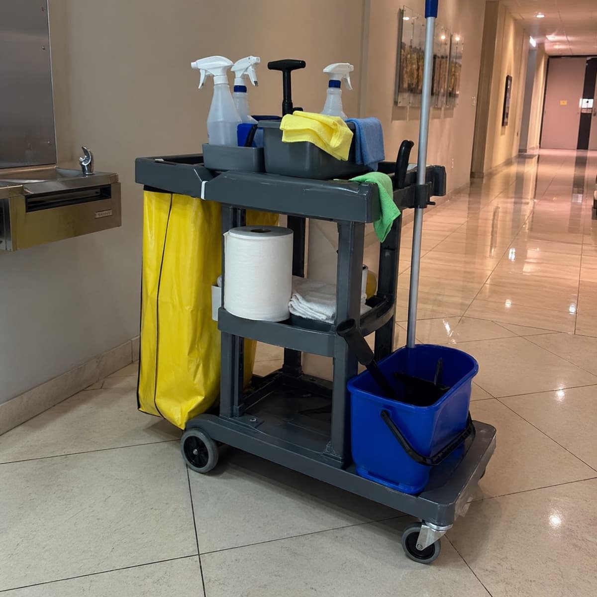 Organized janitorial supplies cart in a commercial hallway